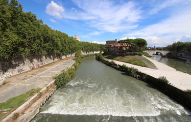 Fototapeta premium Tiber river with wild waters and Tiberina island in Rome. Italy