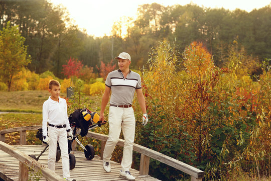 Father with son golfers are walking enjoying autumn lanscape