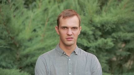 aggressive men. guy on the background of green trees.