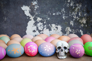 Human skull with colorful Easter eggs, Hen eggs on a wooden tabl