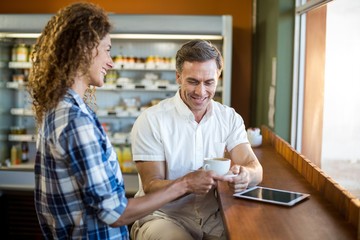 Smiling woman offering a cup of coffee to man 