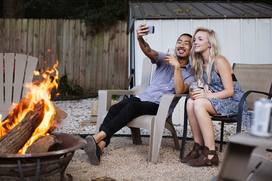 Friends taking selfie while sitting on chairs at yard
