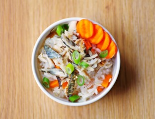 Delicious homemade rice soup with fish and vegetables on a wooden served table ready for breakfast in the morning.