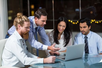 Group of businesspeople discussing over laptop