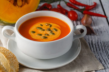 Roasted pumpkin and carrot soup with cream and pumpkin seeds on