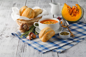 Pumpkin soup in a bowl with fresh pumpkins, garlic and parsley h