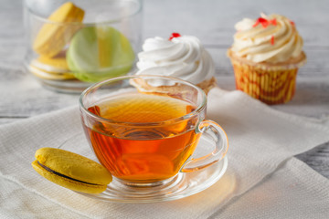 Tasty macaroons with tea on wooden table