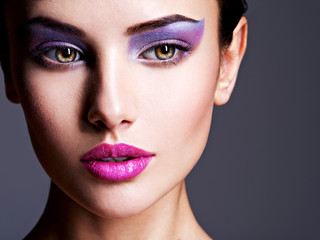 Beautiful girl's face closeup with purple eye make-up. fashion m