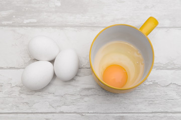 three raw eggs and empty cup