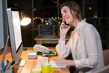 Businesswoman talking on phone while working