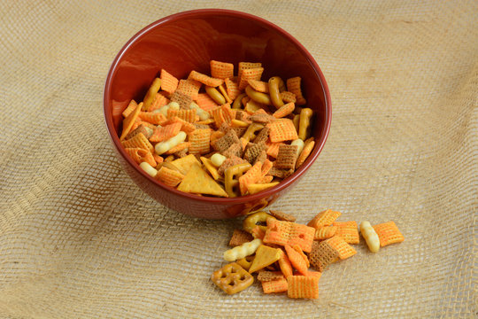 Red Bowl full of cheese flavored party snacks on burlap