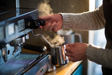 Waiter making cup of coffee at counter in kitchen