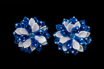 Bows of the white and blue satin ribbons and crystals. Isolated on a black background.
