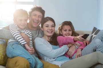 Family watching television while sitting on sofa