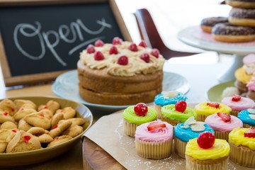 Close-up of various sweet foods on table with open signboard