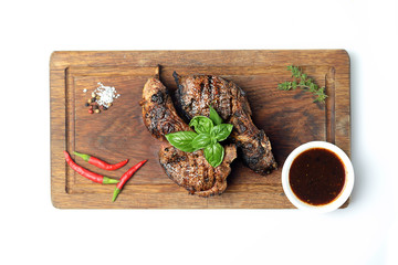 Grilled lamb steak on a cutting board on a white background
