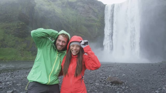 Iceland tourists couple by waterfall Skogafoss. Couple visiting famous tourist attractions and landmarks in Icelandic nature landscape on the Ring Road. RED EPIC SLOW MOTION.