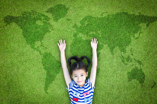 Children's day and clean environment concept. Happy healthy Asian kid having fun on green grass lawn with world map: Elements of this image furnished by NASA.