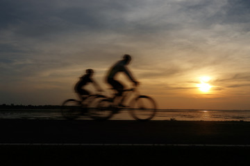 Fototapeta premium Silhouette ride bicycle at sunset. With effect subject movement