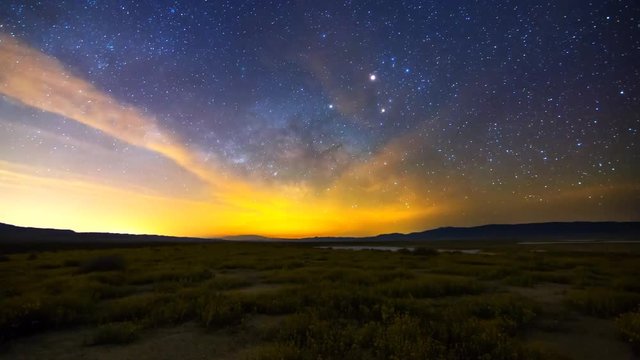 Astrophotography time lapse with tilt up motion of Milky Way galaxy rising over Desert Gold wildflower super bloom 2016 in Carrizo Plain National Monument, California