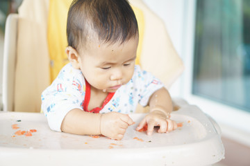 Asian baby eating food by himself