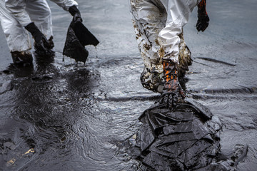 Workers remove crude oil from a beach