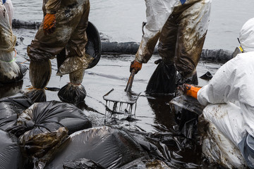 Workers remove crude oil from a beach