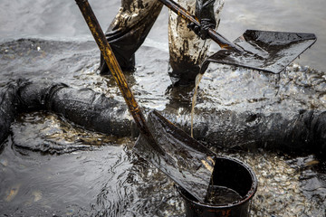 Workers remove crude oil from a beach