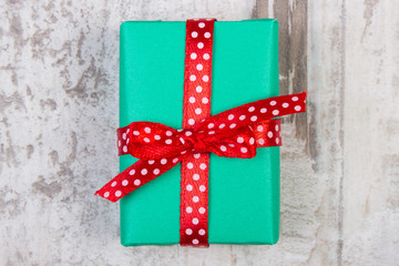 Fototapeta na wymiar Green gift for Christmas or other celebration on wooden plank