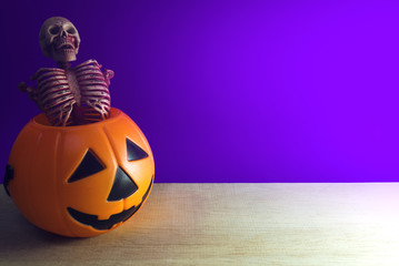 skeleton in orange bucket with purple background