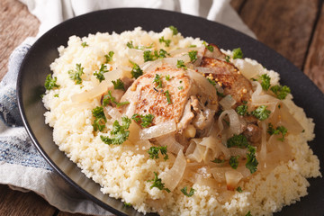 Yassa chicken stewed with marinated onions and couscous close up. horizontal
