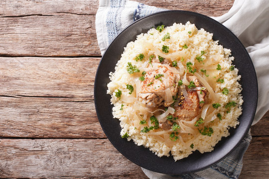 Yassa chicken with onions and garnished with couscous closeup. horizontal top view