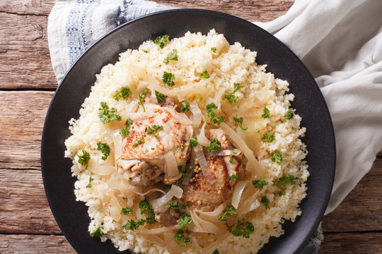 Yassa chicken stewed with marinated onions and couscous closeup. Horizontal top view