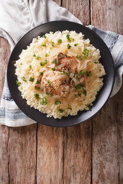 Yassa chicken with onions and garnished with couscous closeup. Vertical top view
