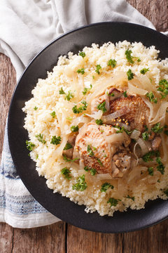 Yassa chicken stewed with marinated onions and couscous closeup. Vertical top view
