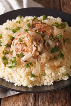 Yassa chicken with onions and garnished with couscous close up. vertical
