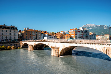 Naklejka premium Morning cityscape view with mountains, river and bridge in Grenoble city on the south-east of France