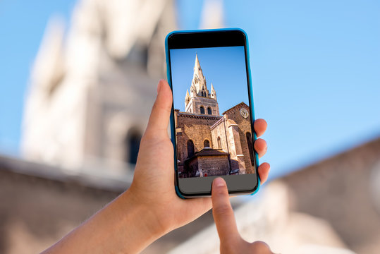 Holding a smart phone with photo of Saint Andrew church tower in Grenoble city in France