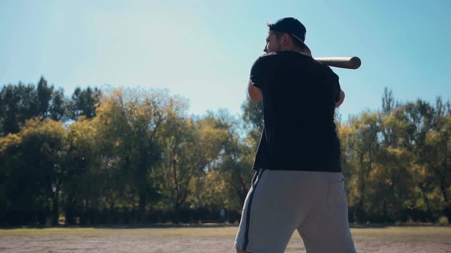 Slowmotion Young Male Batter Standing Ready for Pitch with Baseball Bat Over Shoulder During Casual Baseball Game in Sunny Field with Catcher Crouching in Background in Summer Time.