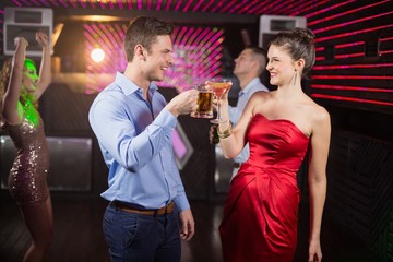 Smiling couple toasting glass of beer and cocktail