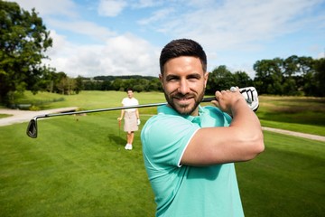 Man standing with golf club in golf course