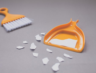 Elimination conceptual-can be write on White mock-up ripped paper in Orange Mini bloom and Dustpan on grey background.Focused the ripped paper on orange dustpan.