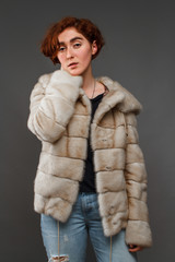 Girl in winter fur coat over gray background