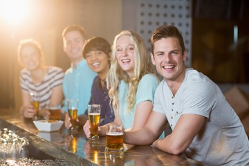 Group of friends having glass of beer at bar counter