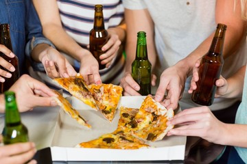 Group of friends having bottle of beer and pizza in party