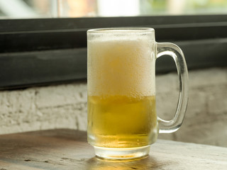 Glass of frosty beer on table in restaurant.