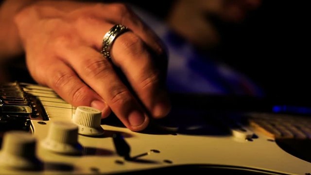 Guy Runs Fingers over Strings of Horizontal Guitar Closeup