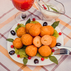 Hot juicy fried cheese balls with sauce on a white plate. Glass of tomato juice.