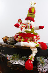 Funny snowman sits on vintage brown coffer with white christmas