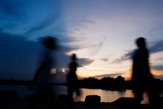 Silhouette and motion blur of people walking at riverside in evening,Cloud Shadow with blue sky